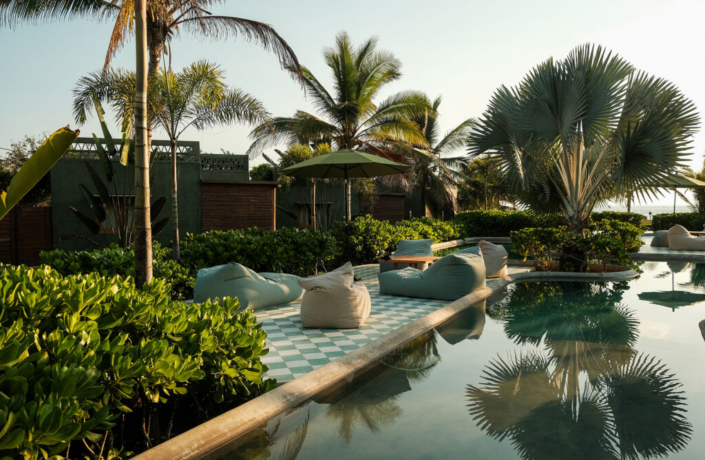 Pool area at Samas La Saladita surrounded by tropical gardens and palm trees on Mexico’s Pacific coast.