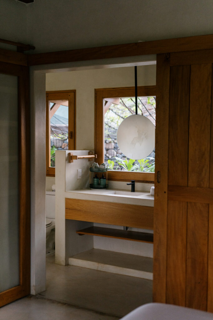 Hotel room at Samas La Saladita with a view of the private ensuite bathroom, featuring sliding wood doors and modern design.