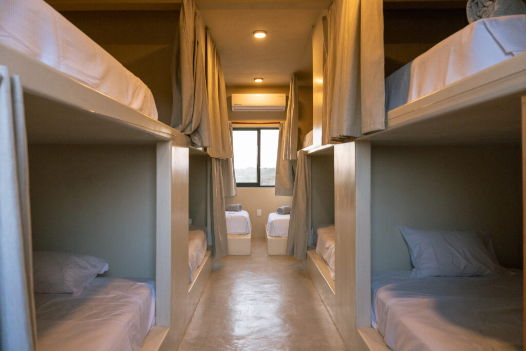 Shared dormitory at Samas Hostel in La Saladita, featuring designer capsule-style bunks with privacy curtains.